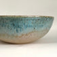 A generously sized stoneware bowl with gentle ripple texturing around the underside of the curve, glazed in a warm sandy tan that shifts to a rich blue-green verdigris near the rim and spills over into the interior of the bowl.