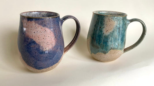A classic coffee mug with a gentle curve to its body.  The belly of the mug is slightly wider than the mouth.  The handle has comfortable contouring to its underside, making for a surer grip in the hand.  Glaze options include an indigo blue-purple atop a shell pink, or a rich verdigris blue-green atop a warm sandy golden brown.